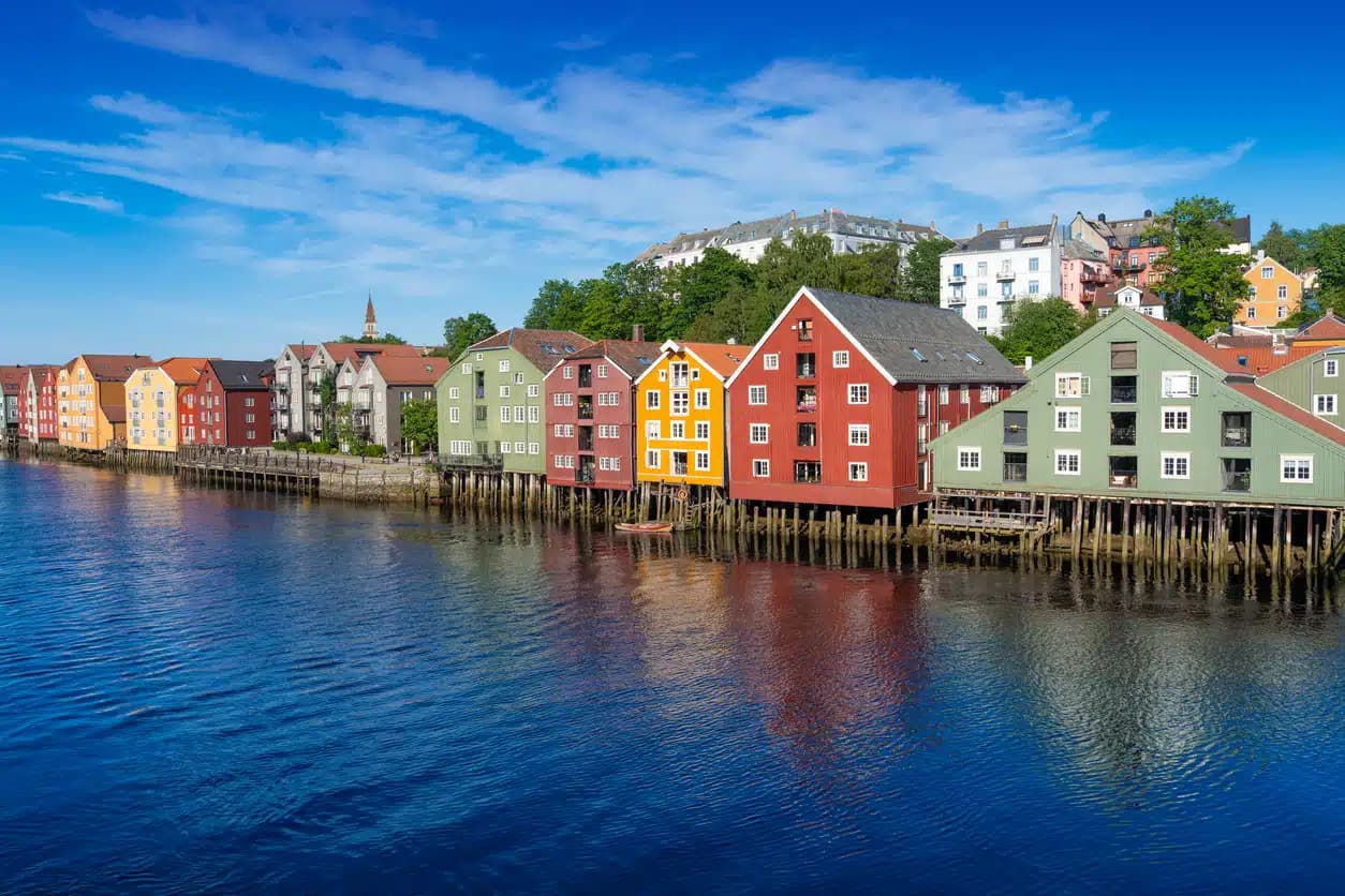Fargerike brygger på påler langs Nidelva i Trondheim, brukt som illustrasjon i artikkel om beste eiendomsmegler i Trøndelag.
